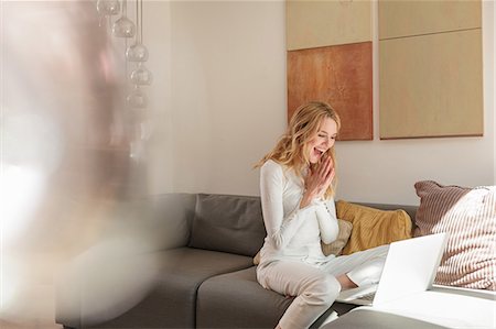 Woman on sofa using laptop looking surprised Stock Photo - Premium Royalty-Free, Code: 649-08714481