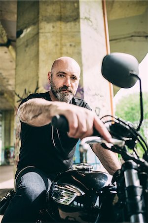 Portrait of mature male motorcyclist sitting on motorcycle under flyover Stock Photo - Premium Royalty-Free, Code: 649-08714714