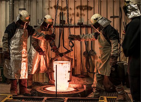 foundry worker - Male foundry workers winching white hot melting pot in bronze foundry Stock Photo - Premium Royalty-Free, Code: 649-08715044