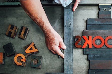 Detail of hand using letterpress machine in book arts workshop, overhead view Stock Photo - Premium Royalty-Free, Code: 649-08744896