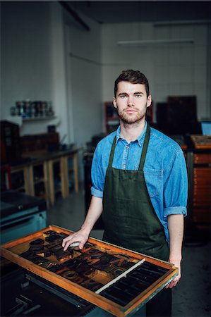 Portrait of young craftsman next to tray of letterpress letters in print workshop Stock Photo - Premium Royalty-Free, Code: 649-08744913