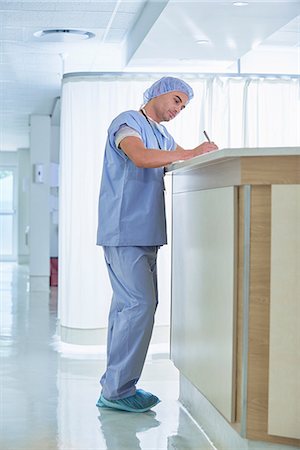 Doctor writing up medical notes at hospital nurses station Stock Photo - Premium Royalty-Free, Code: 649-08745365