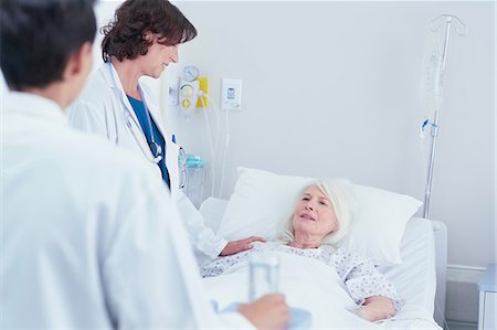 patient comfort - Doctors explaining to senior female patient in hospital bed Stock Photo - Premium Royalty-Free, Code: 649-08745403