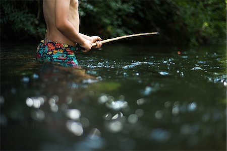 Cropped view of boy waist deep in water holding stick Stock Photo - Premium Royalty-Free, Code: 649-08745641