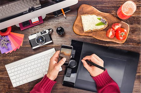 person organizing desk - Overhead view of male hands editing photographs from smartphone on  graphic design tablet using digital pen Stock Photo - Premium Royalty-Free, Code: 649-08745744