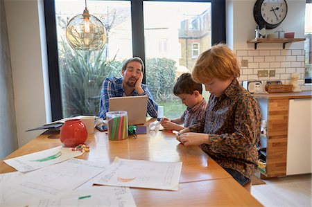 family computer kitchen - Exhausted man at dining table with laptop whilst son colouring Stock Photo - Premium Royalty-Free, Code: 649-08766241