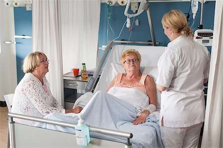 Nurse and visitor tending to patient in hospital bed Photographie de stock - Premium Libres de Droits, Code: 649-08824255