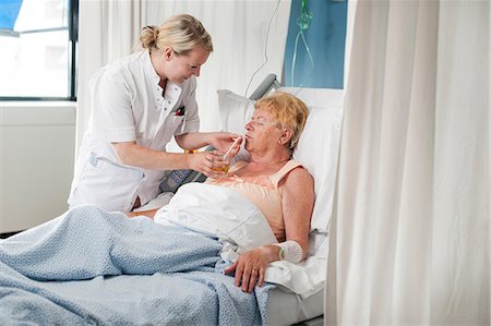 Nurse helping patient in hospital bed take a drink Stock Photo - Premium Royalty-Free, Code: 649-08824257
