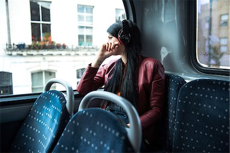 Young woman sitting on bus, wearing headphones, looking out of window Stock Photo - Premium Royalty-Free, Code: 649-08824881