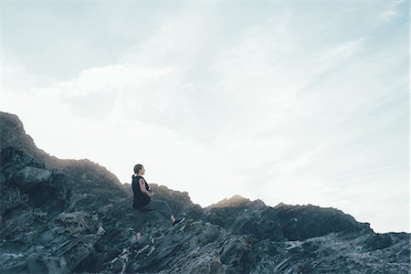 Side view of woman sitting on rocks looking away, Stintino, Sassari, Italy Stock Photo - Premium Royalty-Free, Code: 649-08823958