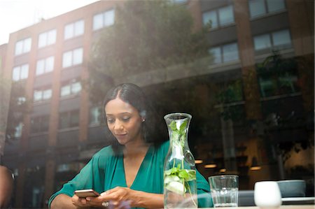 simsearch:649-07238896,k - Mid adult woman reading smartphone texts in cafe window seat Stock Photo - Premium Royalty-Free, Code: 649-08840292