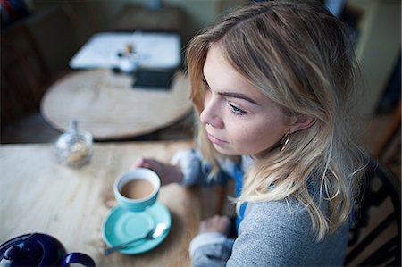 simsearch:614-08392638,k - Young woman sitting in cafe, holding tea cup, thoughtful expression on face Stock Photo - Premium Royalty-Free, Code: 649-08840433