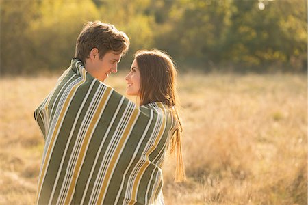 simsearch:649-08239088,k - Young couple in rural setting, wrapped in blanket, face to face, smiling Stock Photo - Premium Royalty-Free, Code: 649-08840569
