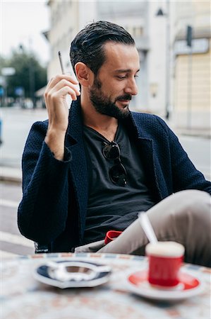 simsearch:649-07238896,k - Mid adult man smoking cigarette at sidewalk cafe Stock Photo - Premium Royalty-Free, Code: 649-08840796