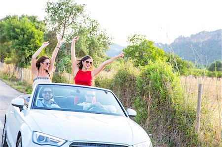 simsearch:649-07280823,k - Two young female friends standing waving whilst driving on rural road in convertible, Majorca, Spain Stock Photo - Premium Royalty-Free, Code: 649-08840801