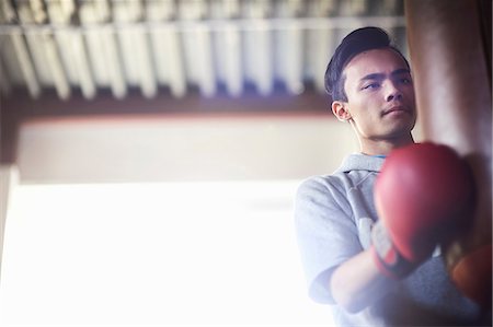 simsearch:614-00657246,k - Young male boxer punching punch bag in gym Stock Photo - Premium Royalty-Free, Code: 649-08859811