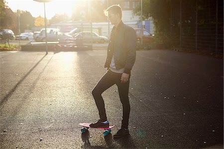simsearch:649-07710443,k - Young male skateboarder with skateboard on sunlit street Stock Photo - Premium Royalty-Free, Code: 649-08859822