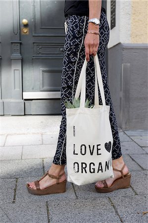 Waist down view of woman strolling on street carrying organic shopping bag Stock Photo - Premium Royalty-Free, Code: 649-08894245