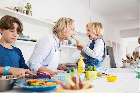 Girl feeding mother asparagus at kitchen table Foto de stock - Sin royalties Premium, Código: 649-08894308