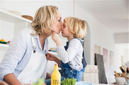 Mature woman kissing daughter at kitchen table Stock Photo - Premium Royalty-Free, Code: 649-08894309