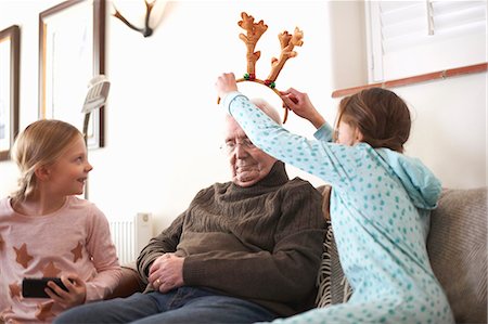 simsearch:640-03260410,k - Sisters putting reindeer antlers on sleeping grandfather Stock Photo - Premium Royalty-Free, Code: 649-08894380