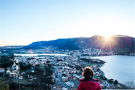 simsearch:649-09078617,k - Rear view of boy watching sunset over mountains and town by lake, Italy Stock Photo - Premium Royalty-Free, Code: 649-08894415