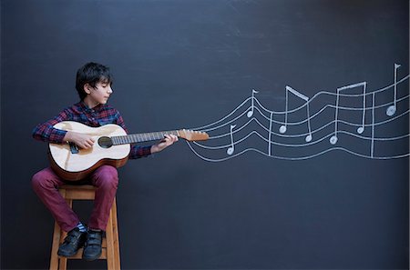 represent - Boy playing guitar in front of chalkboard wall with showing musical notation Stock Photo - Premium Royalty-Free, Code: 649-08894441
