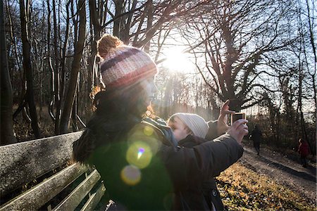 Mother sitting on bench with baby boy, taking selfie with smartphone Stock Photo - Premium Royalty-Free, Code: 649-08894797