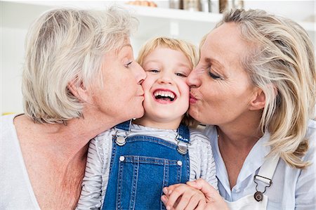 Portrait of girl being kissed on cheek by mother and grandmother in kitchen Stock Photo - Premium Royalty-Free, Code: 649-08894888