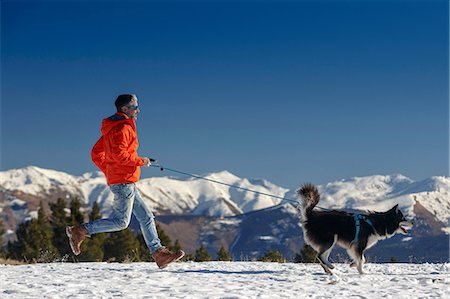 simsearch:400-05724021,k - Man running with dog in snow covered mountain landscape Stock Photo - Premium Royalty-Free, Code: 649-08900385