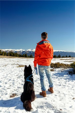 simsearch:400-05724021,k - Rear view of man with dog looking out at snow covered landscape Stock Photo - Premium Royalty-Free, Code: 649-08900389