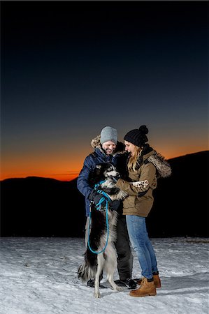 simsearch:400-05724021,k - Couple playing with dog in snow at night Stock Photo - Premium Royalty-Free, Code: 649-08900399