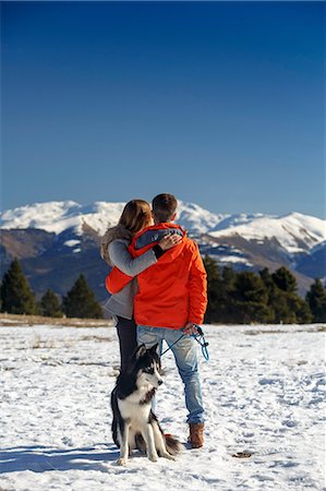 simsearch:400-05724021,k - Rear view of romantic couple with dog looking out at snow covered mountain landscape Stock Photo - Premium Royalty-Free, Code: 649-08900390