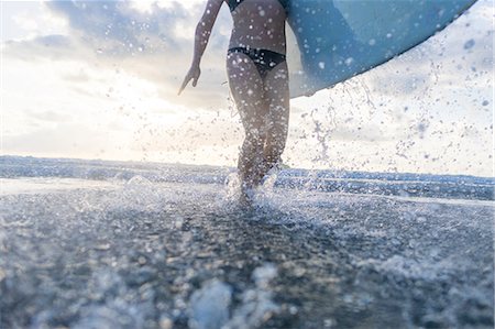 simsearch:649-08900720,k - Neck down view of woman carrying surfboard and splashing in sea, Nosara, Guanacaste Province, Costa Rica Stock Photo - Premium Royalty-Free, Code: 649-08900716