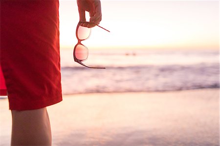 simsearch:649-08900720,k - Rear cropped view of woman's hand holding sunglasses on beach at sunset, Nosara, Guanacaste Province, Costa Rica Stock Photo - Premium Royalty-Free, Code: 649-08900735