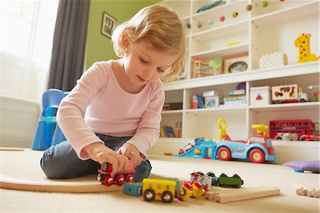 Female toddler playing with toy train on playroom floor Photographie de stock - Premium Libres de Droits, Code: 649-08901005