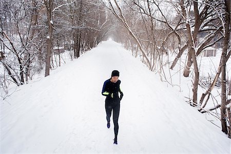 simsearch:649-07437947,k - Young female runner in knit hat running in snow covered tree lined park Stock Photo - Premium Royalty-Free, Code: 649-08901225