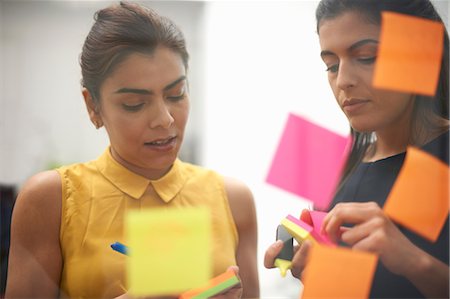 simsearch:614-06718107,k - Two businesswomen writing on sticky notes for office glass wall Stock Photo - Premium Royalty-Free, Code: 649-08901449