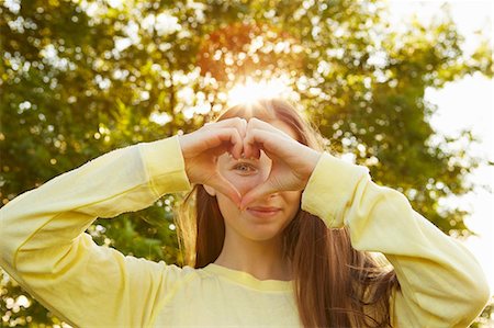 symbolism - Portrait of girl making heart shape with hands in park Stock Photo - Premium Royalty-Free, Code: 649-08901499