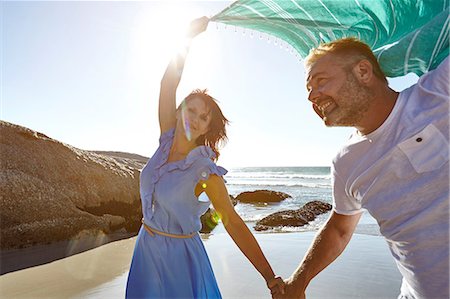 simsearch:614-07239972,k - Mature couple holding hands on beach, woman holding sheer scarf in air Stock Photo - Premium Royalty-Free, Code: 649-08901842