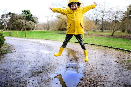 people boys - Boy in yellow anorak jumping above puddle in park Stock Photo - Premium Royalty-Free, Code: 649-08902297