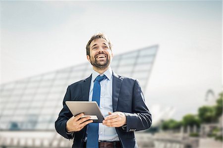 simsearch:649-07560130,k - Happy businessman with digital tablet looking up in city Stock Photo - Premium Royalty-Free, Code: 649-08924228