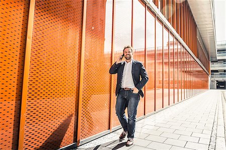 simsearch:859-06710917,k - Businessman making smartphone call while strolling outside office building Stock Photo - Premium Royalty-Free, Code: 649-08924222
