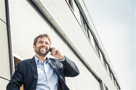 Businessman making smartphone call outside office building Stock Photo - Premium Royalty-Free, Code: 649-08924243