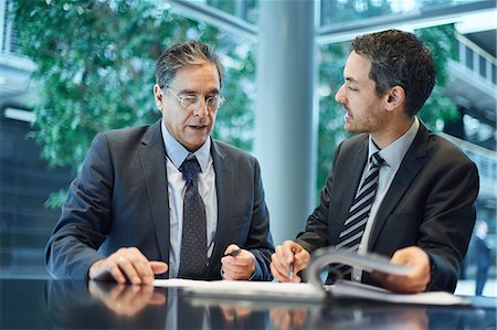 simsearch:655-03458001,k - Two businessmen meeting over paperwork at office desk Stock Photo - Premium Royalty-Free, Code: 649-08924269