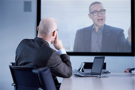 simsearch:649-07238396,k - Businessman watching office conference call Stock Photo - Premium Royalty-Free, Code: 649-08924346