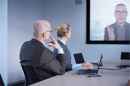 simsearch:649-07238396,k - Businessman and woman watching office conference call Stock Photo - Premium Royalty-Free, Code: 649-08924348