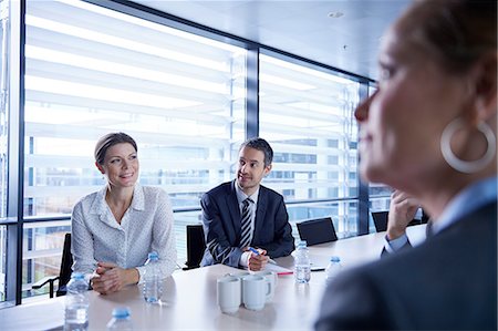 Over shoulder view of businesswomen and men listening at office meeting Stock Photo - Premium Royalty-Free, Code: 649-08924355