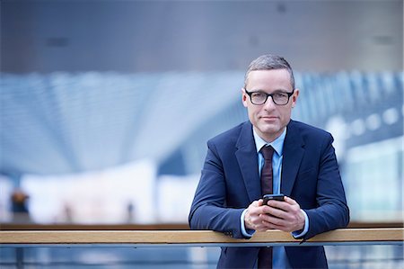 simsearch:649-07520071,k - Portrait of businessman holding smartphone on office balcony Stock Photo - Premium Royalty-Free, Code: 649-08924371