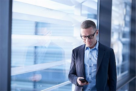 simsearch:649-06845199,k - Businessman looking at smartphone in office Stock Photo - Premium Royalty-Free, Code: 649-08924447